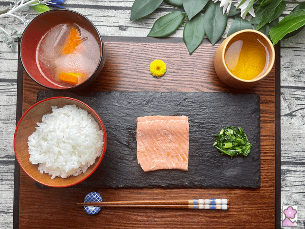 Poached Salmon with Soup and Rice On a tray. There are also pickles and tea.