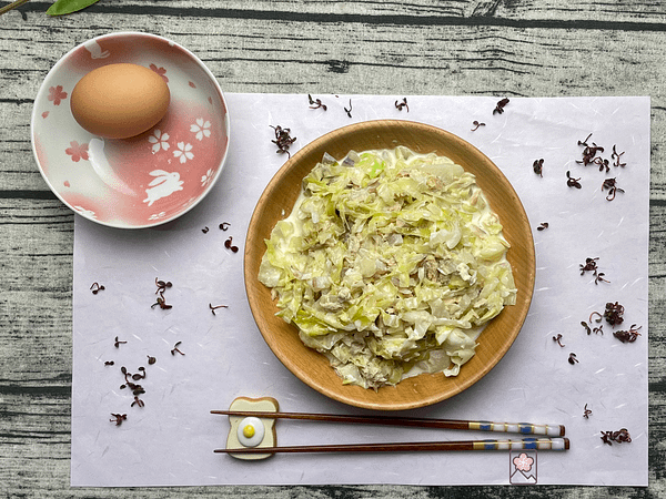 Tuna and cabbage salad Served in a bowl with an uncracked egg behind it in another bowl.