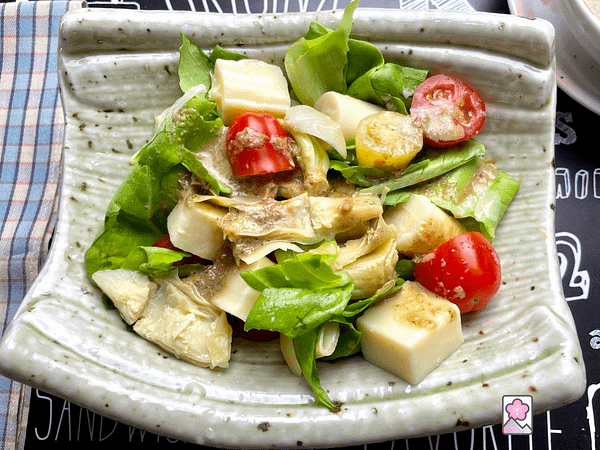 Hearts of Palm Salad drizzled with dressing in a ceramic rectangular bowl