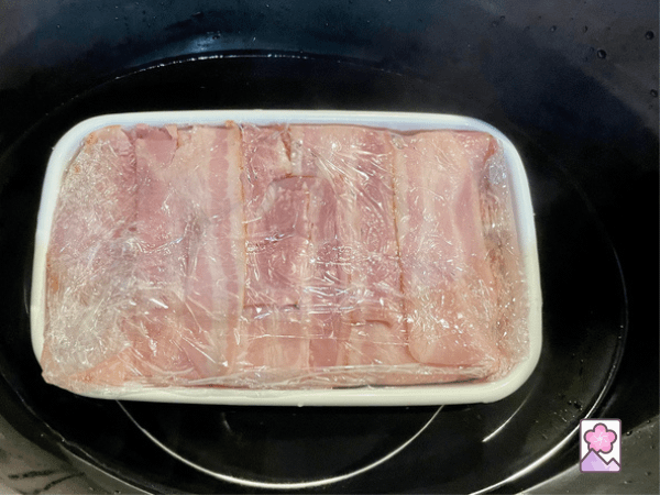 Terrine sitting on a ring in the slow cooker, partially immersed in boiling hot water