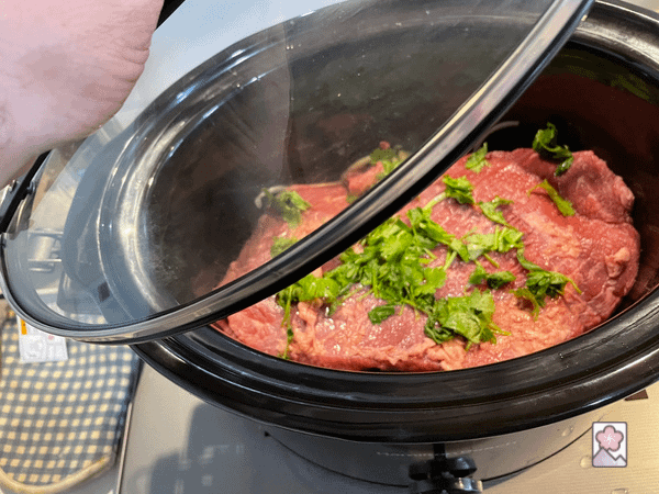 Brisket in a slow cooker with the lid being put on prior to cooking