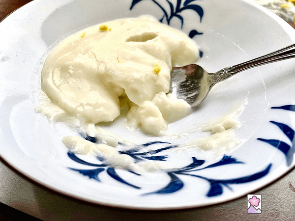 A bowl of Lemon Kudzu pudding halfway eaten. A spoon is buried in the pudding scooping up more.