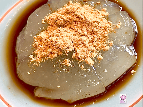 Kuzumochi on a ceramic plate topped with ground soybeans and brown sugar syrup