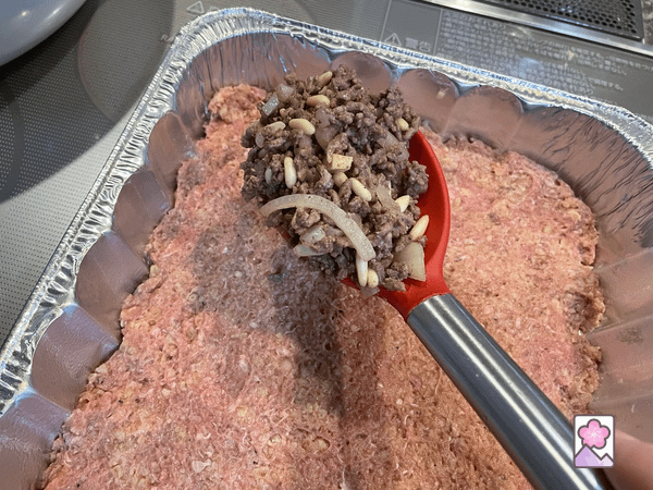 Spooning filling over the bottom layer of bulgur dough