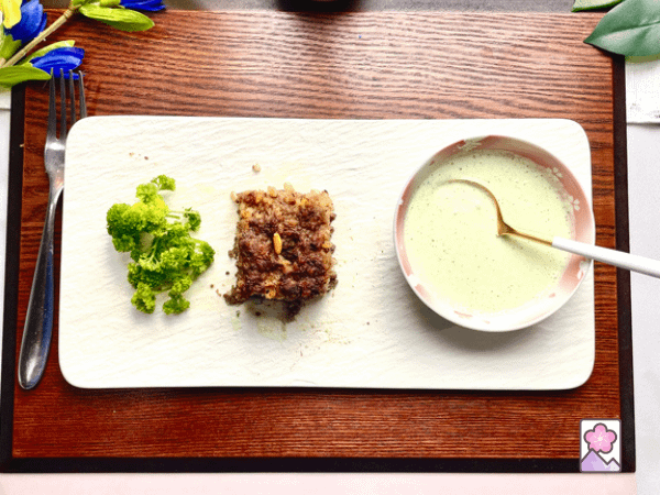 Kibbeh with Greek yogurt sauce amd parsley on a rectangular ceramic plate