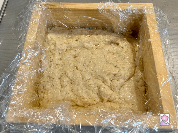 Goma tofu in a square wooden mold lined with plastic wrap
