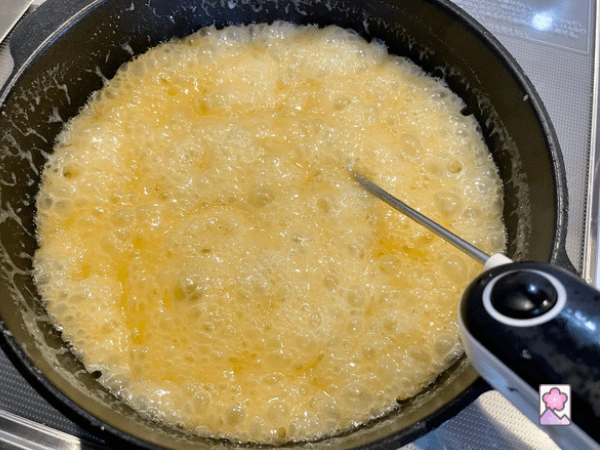 Caramel boiling in a saucepan with a thermometer inserted into the bubbling mixture