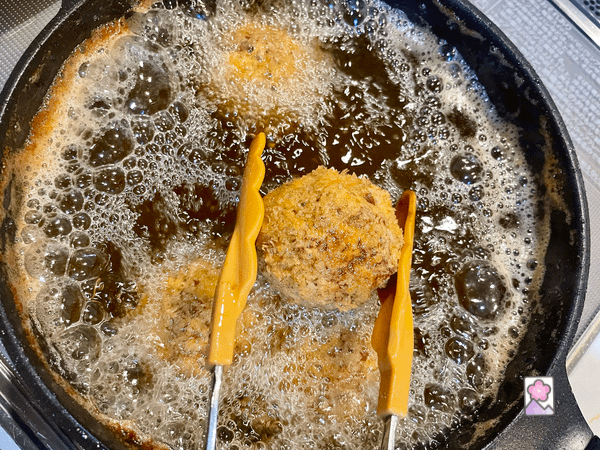 A mini Scotch Egg being lifted out of boiling oil after cooking