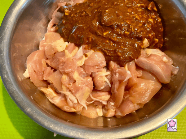 Chicken in a bowl with a marinate paste resting on top