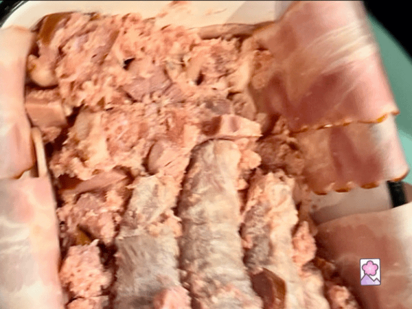 Pressing down on the loaf mixture with a gloved hand to remove the air bubbles