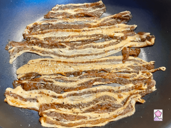 Uncooked bacon in a skillet