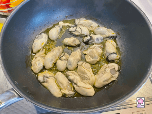 Oysters frying in mustard oil in a large skillet