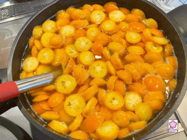Kumquat rounds simmering in syrup in a large saucepan