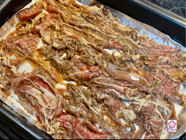 Bacon ready for baking, lined up on a tray