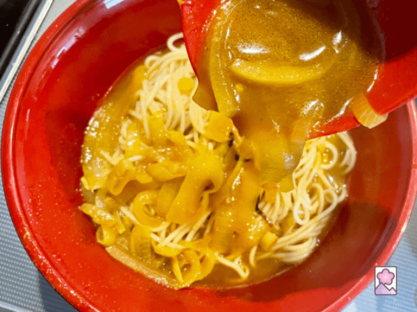 Spooning sauce over ramen