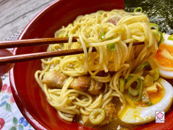 Picking up a big pile of savory curry noodles with chopsticks.