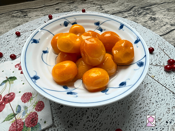 A small bowl of poached Kinkan in a round ceramic bowl on a circular shaped lace placemat