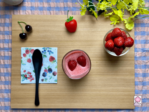 Strawberry mousse in a glass topped with a strawberry. There is a glass bowl full of fresh strawberries nearby