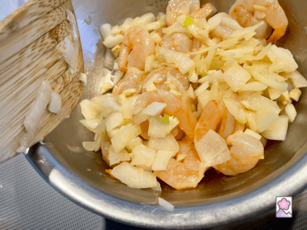 Cooked Shrimp, onions and garlic are set to the side in a metal bowl