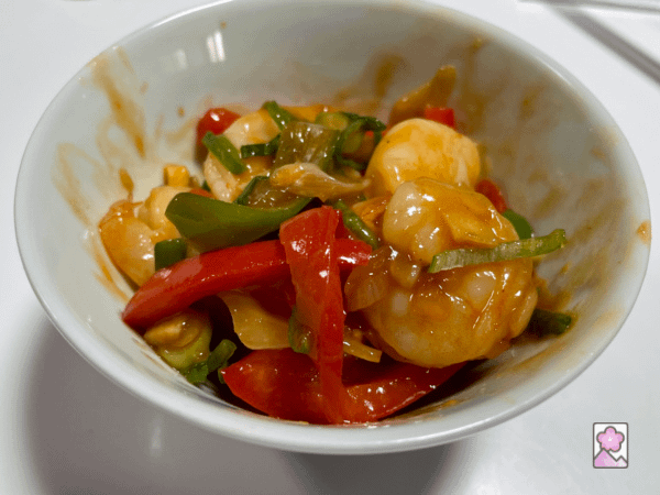 A small bowl of shrimp and chili sauce is loaded with shrimp and vegetables