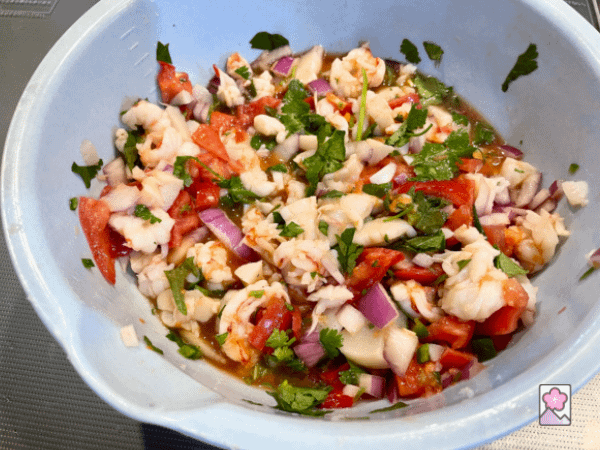 The ceviche is marinating in the dressing in a large plastic bowl