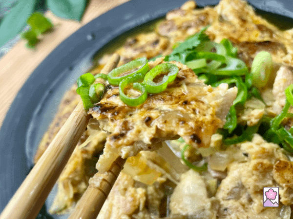 A piece of Roast pork egg foo young in chopsticks