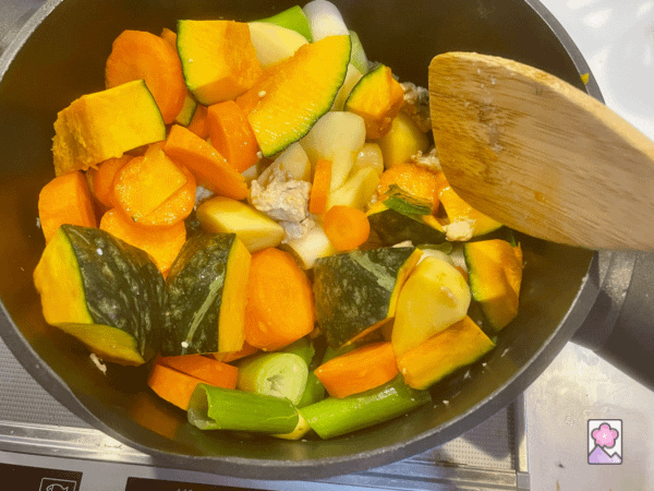 Kabocha stew veggies and chicken are being stirred in a pot