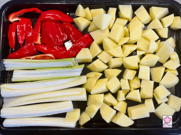 Veggies cut into bite size pieces on a roasting tray
