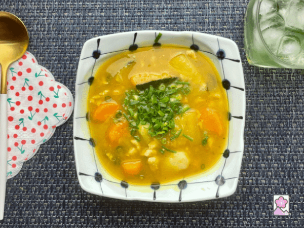 Kabocha stew served in a bowl with some green iced tea in a glass