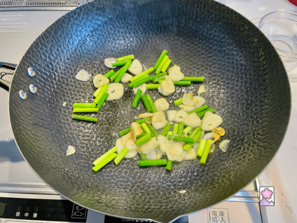 Garlic and Garlic stalks frying in oil in a wok