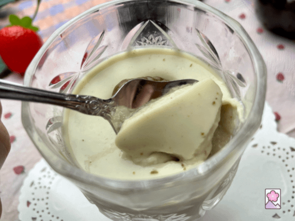 Spooning some Panna cotta out of a glass goblet
