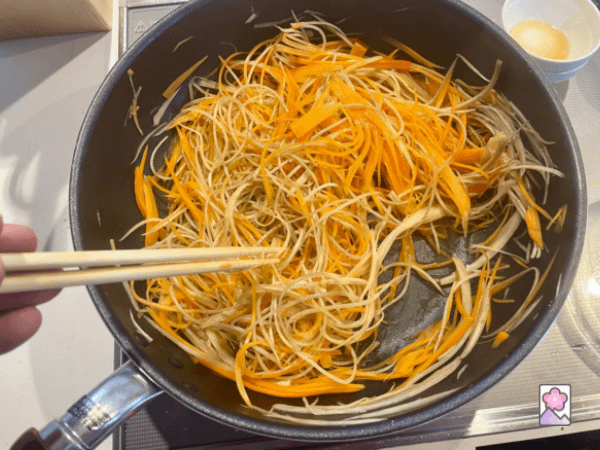 Stir frying gobo and carrot in a wok