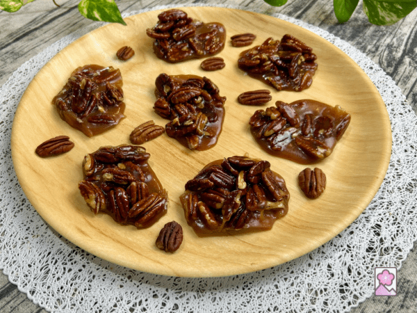 A plate with 7 Caramel Pecan Chews with some pecans also on the plate.
