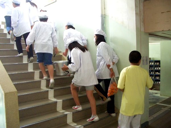 Kanko* from Nagasaki, JAPAN, CC BY 2.0 <https://creativecommons.org/licenses/by/2.0>, via Wikimedia Commons Students carry lunch up the stairs