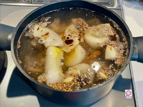 Pho beef broth in a stock pot are being heated to a boil