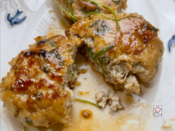 Hiroshima Maple Chicken Sausage is cut in two as the juice runs out onto a plate