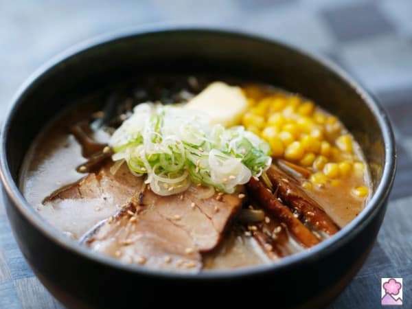 Ramen soup topped with corn, pork, scallions, and vegetables.