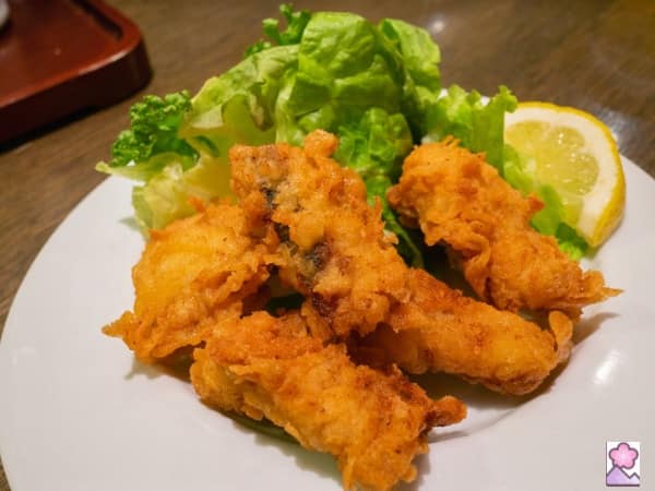 4 pieces of bones fried chicken- Zangi- served with lettuce and a lemon wedge on a white plate