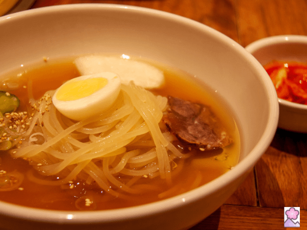 Morioka Reimen in a wooden bowl topped with egg and kimchi