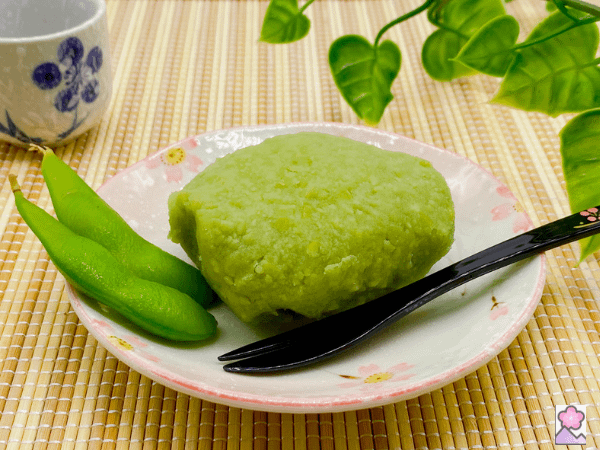 Sunday mochi on a plate with a small fork. 2 edamame posts are to the left of the mochi on the same plate.