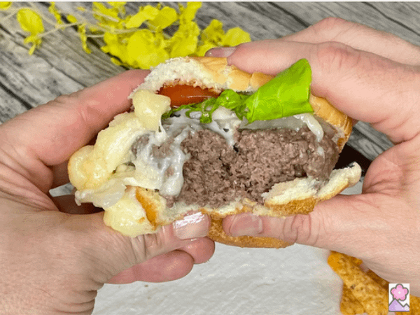 A juicy steamed cheeseburger on a bun with a bit\e taken out.