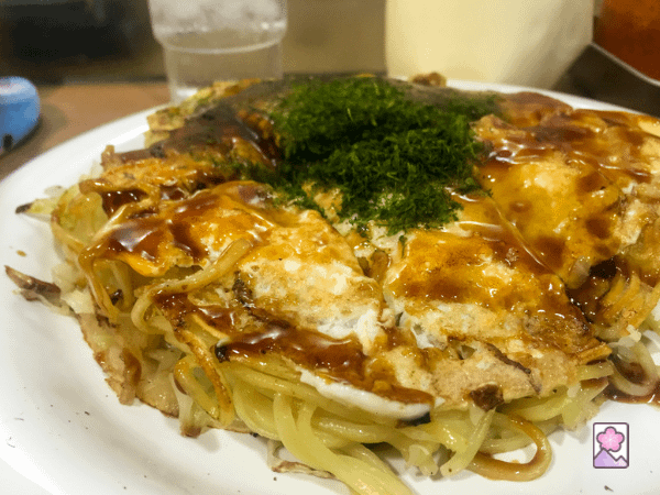Hiroshima Okonomiyaki is a noodle pancake loaded with local seafood. It’s plated and ready to eat.