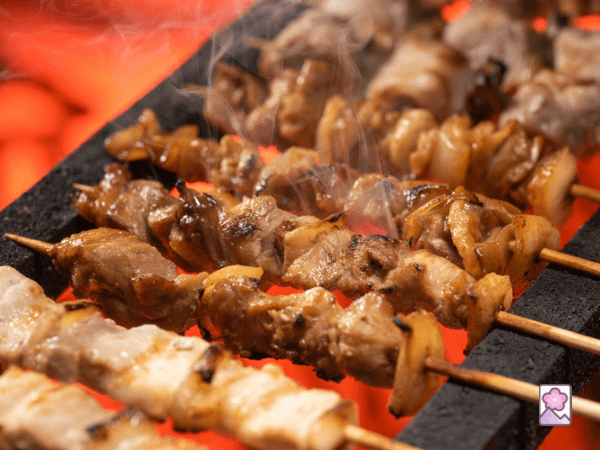 Yakitori on skewers cooking over an open flame