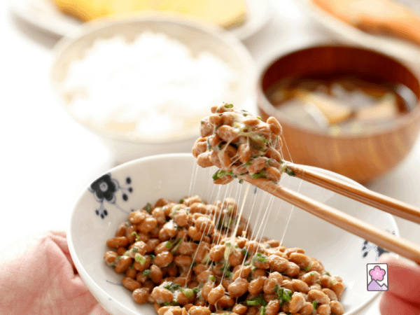 Natto in a small plate being eaten with chopsticks