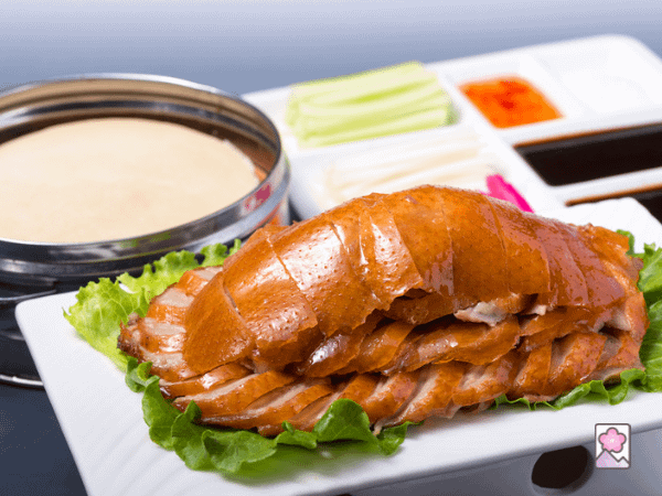 Succulent Peking Duck on a platter with crepes in the background 
