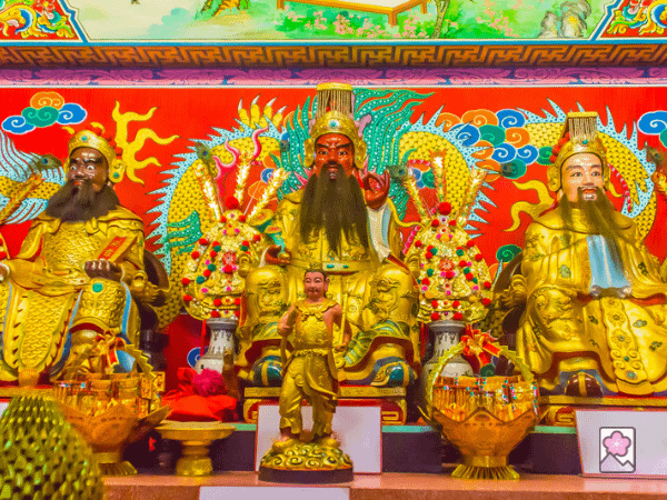 An ornate statue of Guan Yu dressed in gold with advisors on both sides