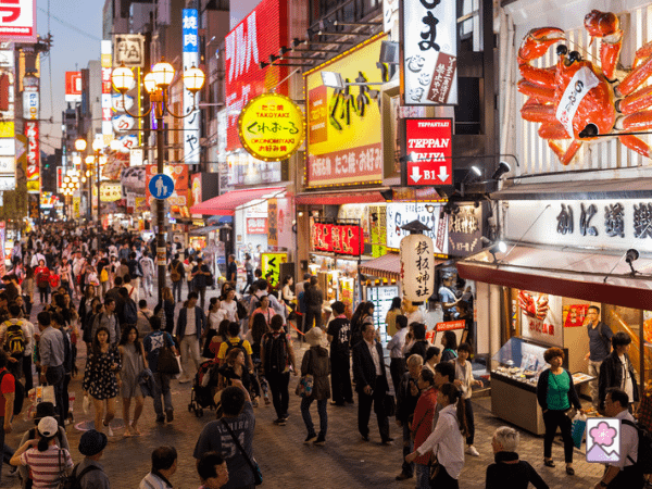 A street in Osaka and its many restaurants advertised with banners, lanterns, and street signs