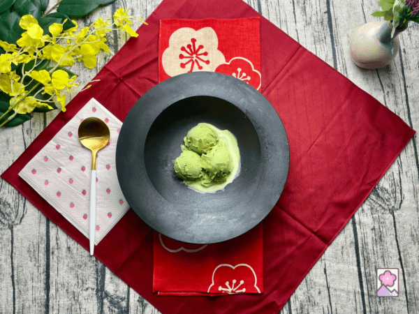 3 scoops of matcha green tea ice cream in a large bowl with a Japanese place setting and a gold plated spoon.