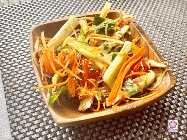 Japanese Celery Salad in a wooden single serving bowl on a thatched place mat
